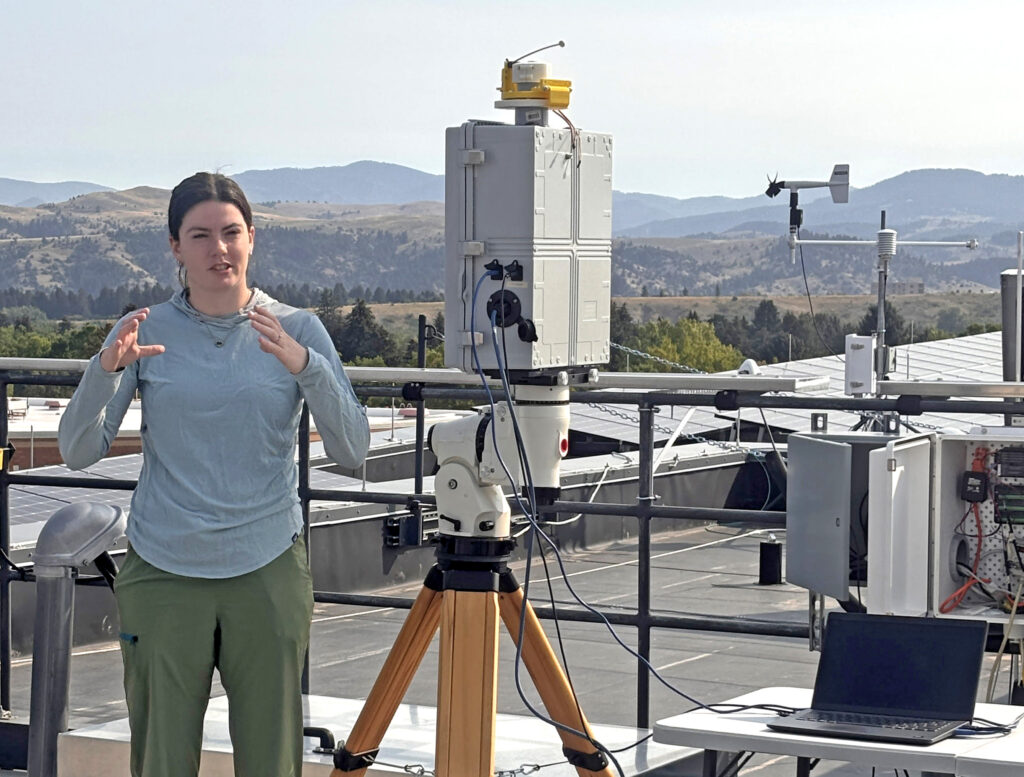 a woman discussing a sensor that is placed on a rooftop next to her