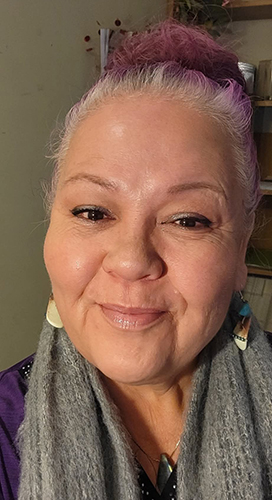 a woman wearing earrings and her hair pulled back and smiling at the camera