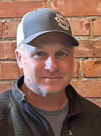 A man wearing a baseball cap and smiling at the camera