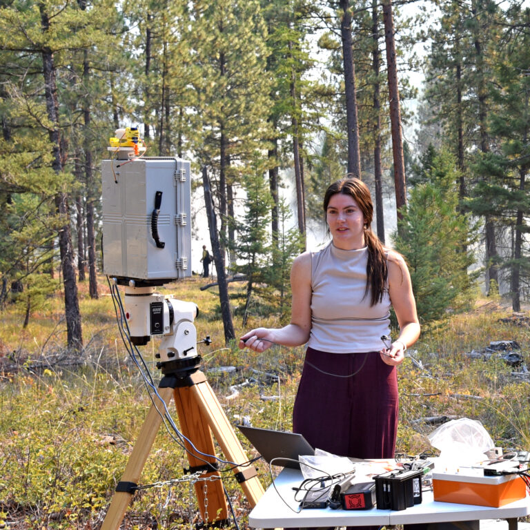 a woman stands next to a photometer in a forest setting